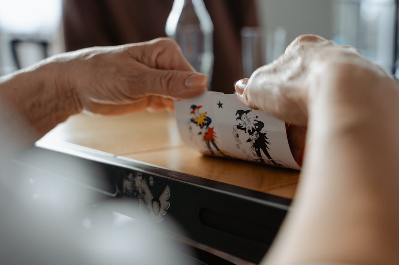Hands holding and playing cards in a classic card game setting, indoors.